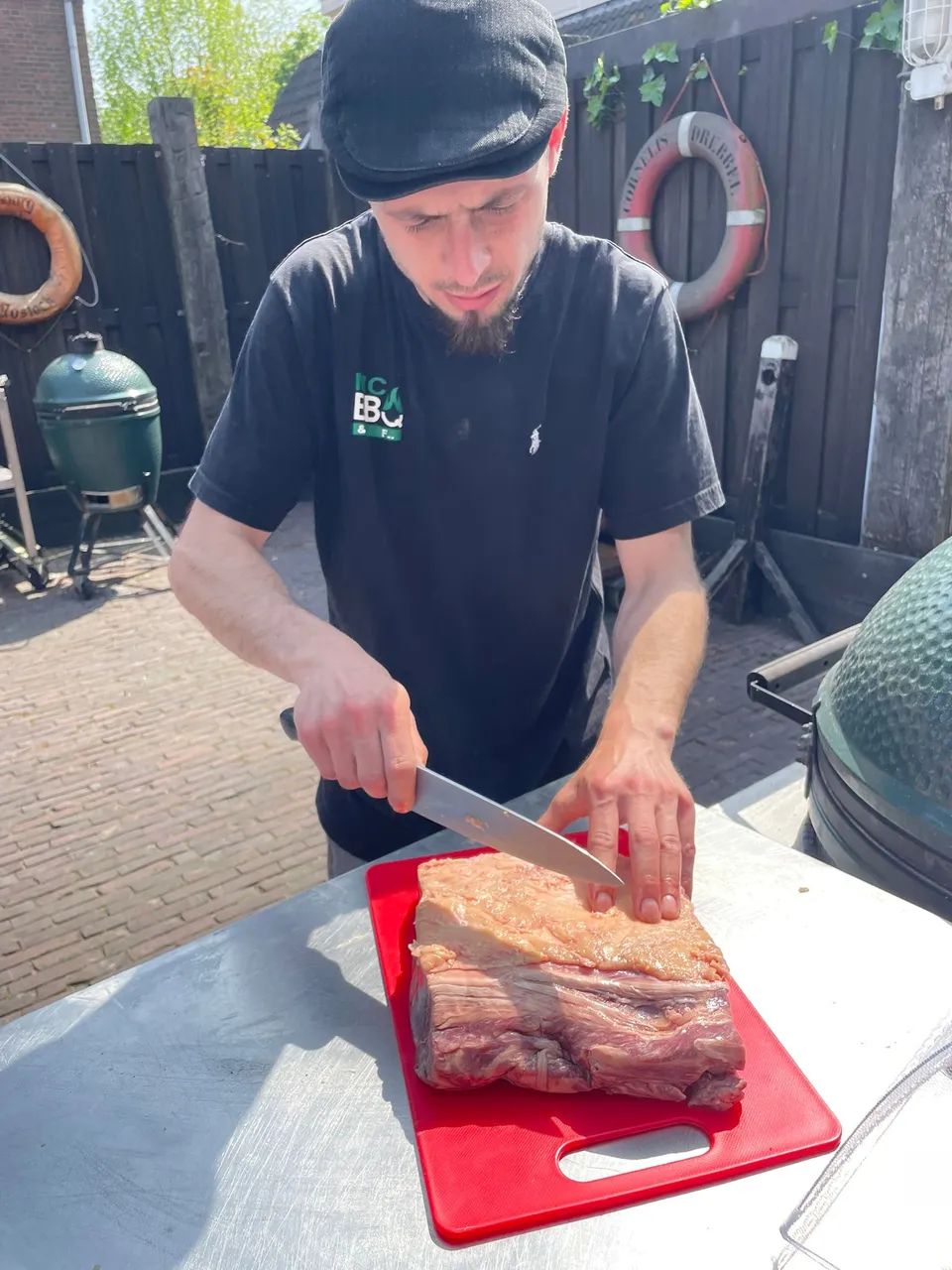 Mitch snijdt vlees aan de werktafel naast een barbecue